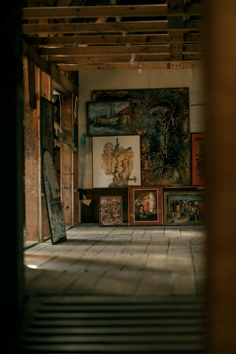 Paintings leaning against studio walls with exposed beams.